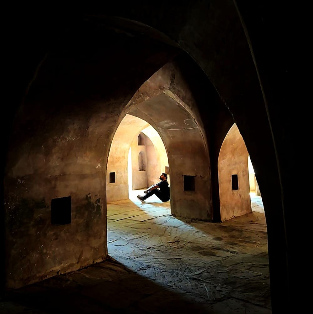 Umang Pokharna, CURWE founder, seated in a sunlit stone archway